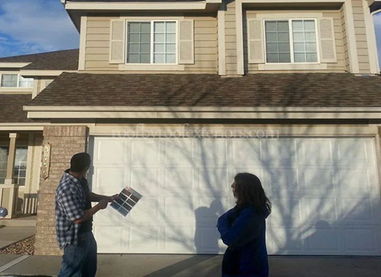 Homeowners comparing shingle colour samples outside their garage